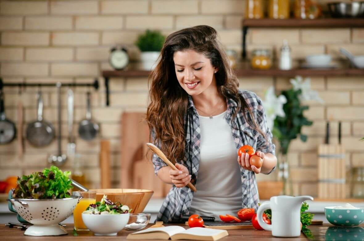 Mulher cozinha alimentos ricos em vitamina para cabelo e unha