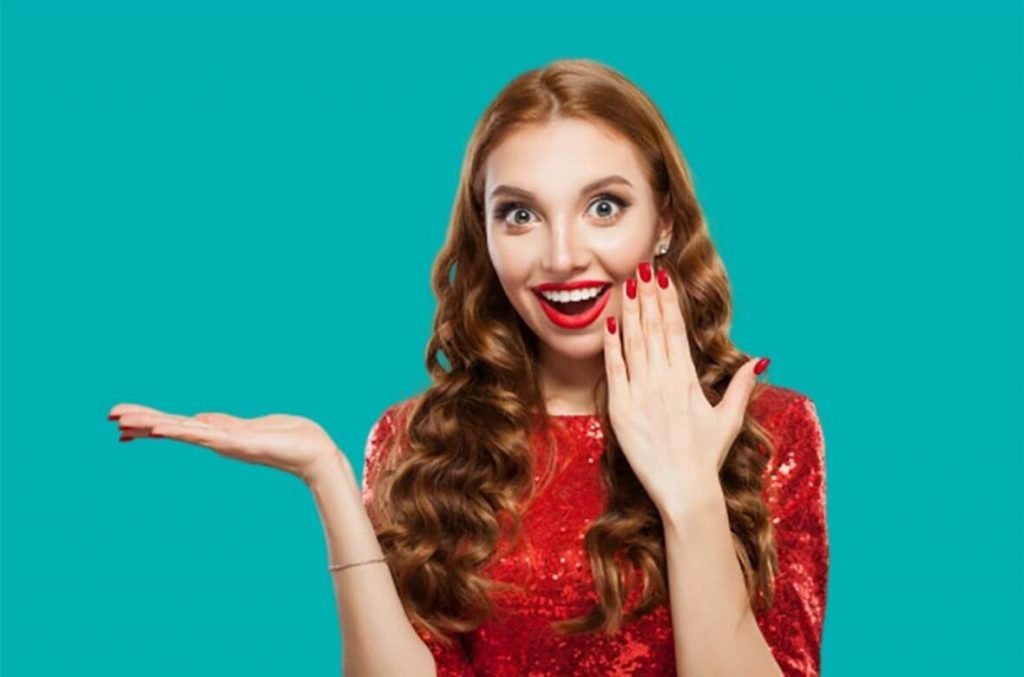 Mulher sorridente mostra suas unhas fortalecidas e seus cabelos volumosos, frutos da ingestão de cisteína